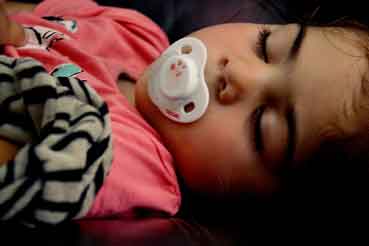 Sleeping Child using a pacifier and holding a blanket