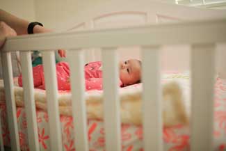 Mother with postpartum depression next to infant in crib